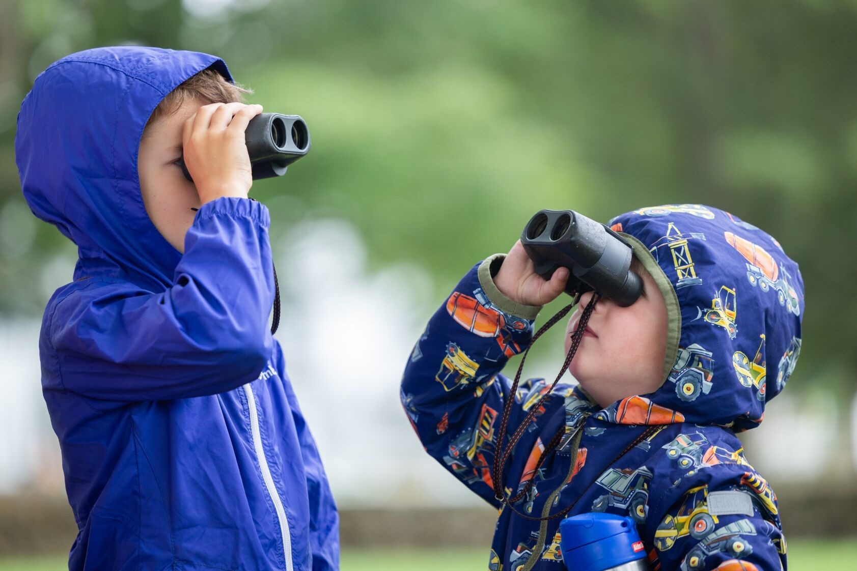 Two children peer through binoculars