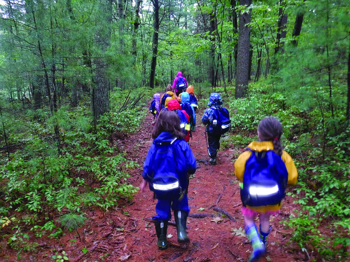 Group of children walking down a trail in the woods at a Trustees property