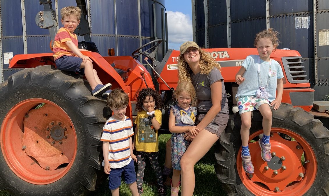 Campers with a counselor sitting on a tractor outdoors at The FARM Institute (TFI) Summer Camp