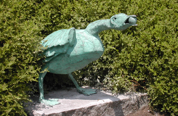 a funny sculpture of a goose with a ball in their mouth