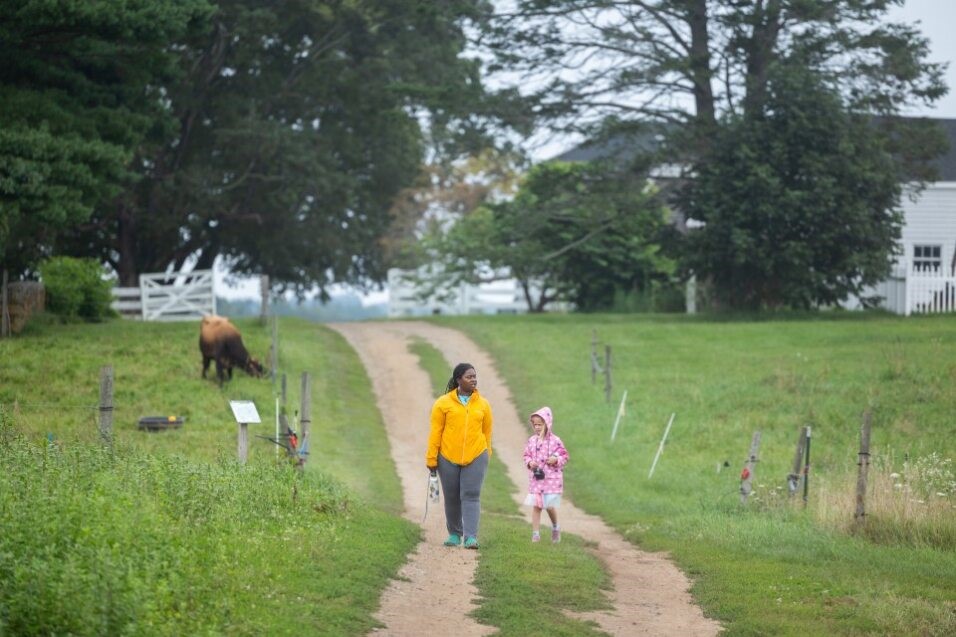 A camper and a counselor walk down a farm path