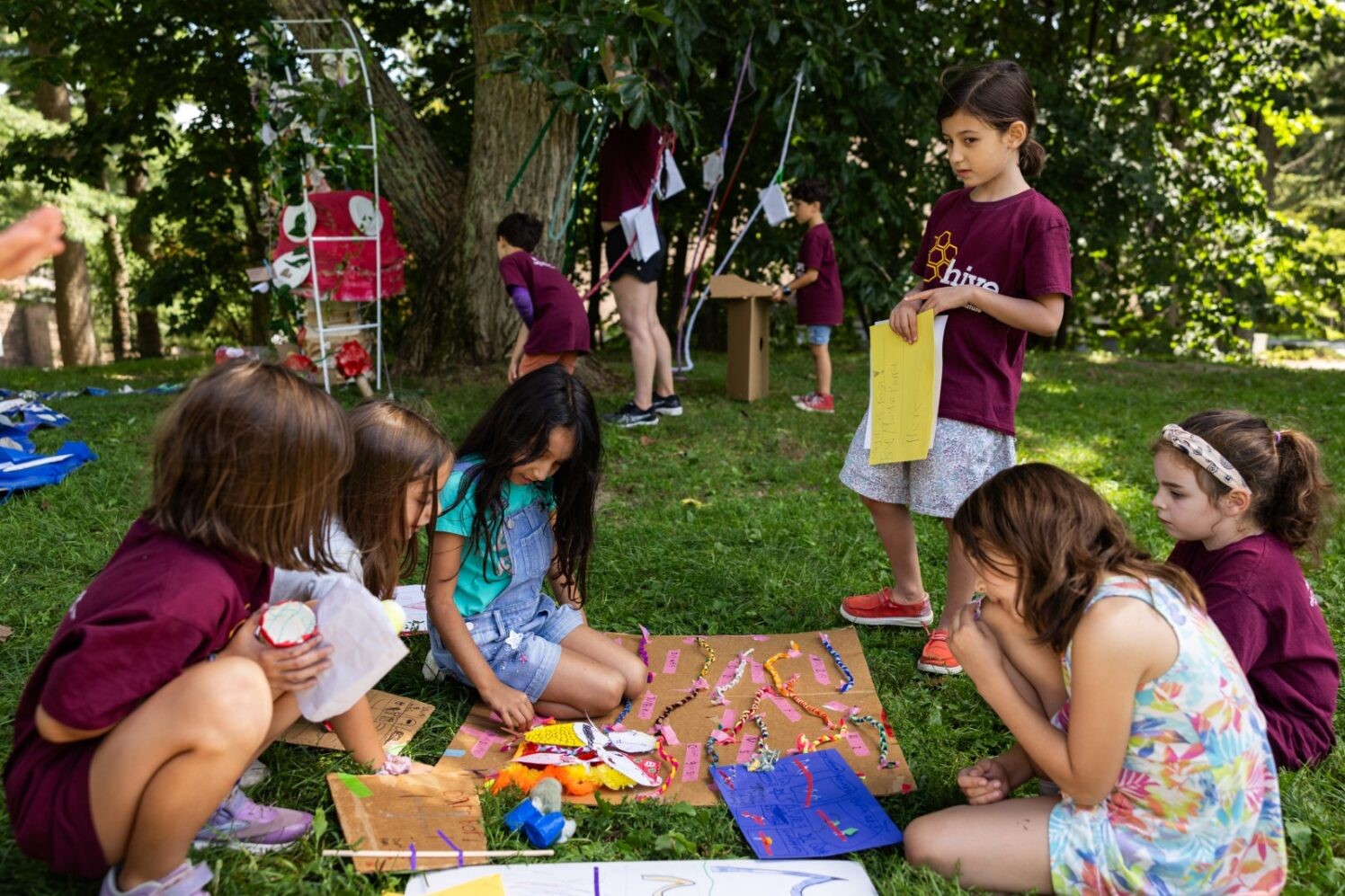 Children paint a canvas laid on the grass