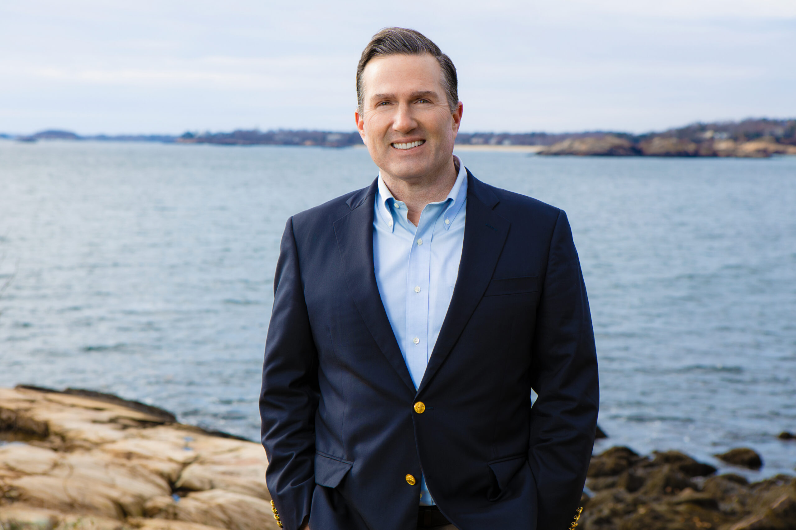 John Judge standing on the coast with rocks and water in the background