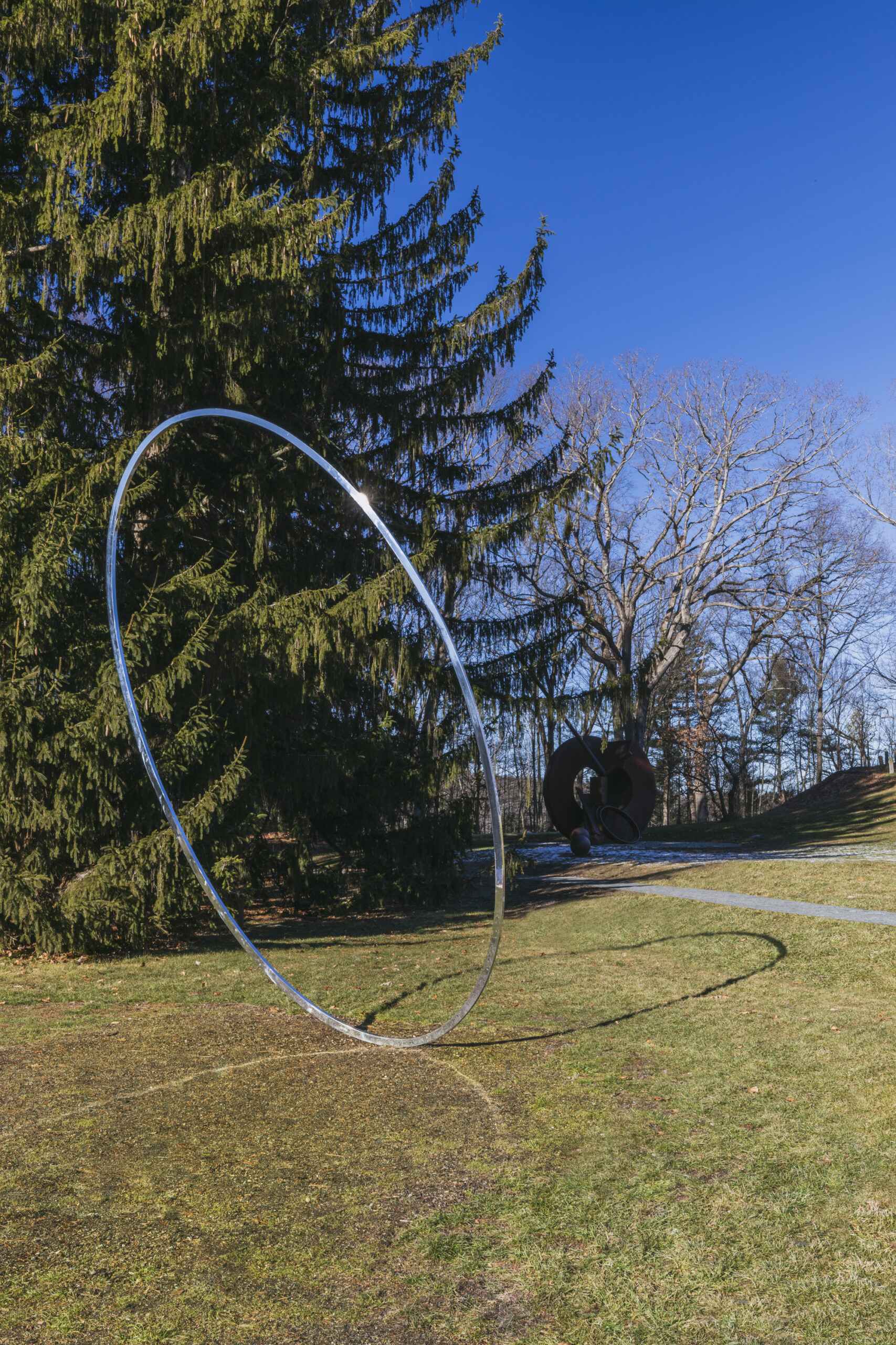a circular sculpture with a mirrored finish, leaning to one side