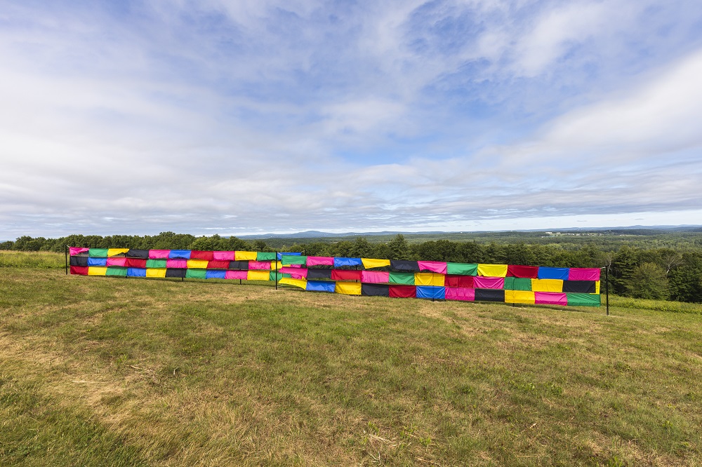 a colorful banner sits on a hill with blue sky and clouds in the background