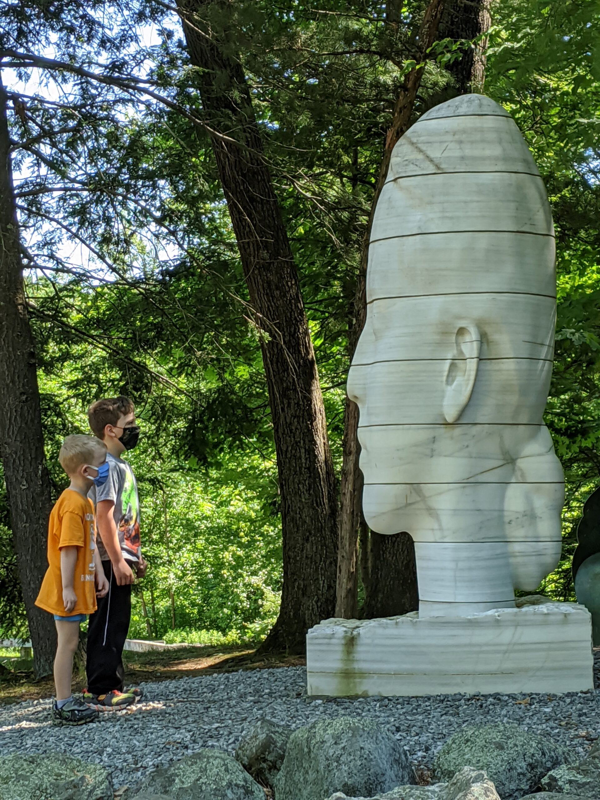 two young children look at a statue of a large head at deCordova Sculpture Park and Museum
