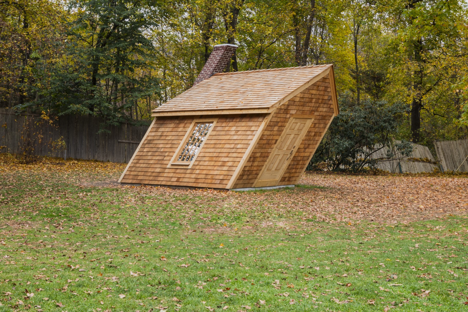 A slanted cabin with shingles and a brick chimney in the style of Thoreau's cabin at Walden