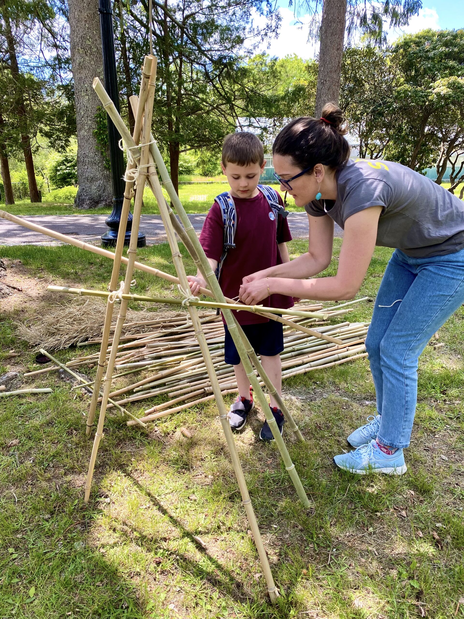 An adult and child work together to build a structure made of bamboo