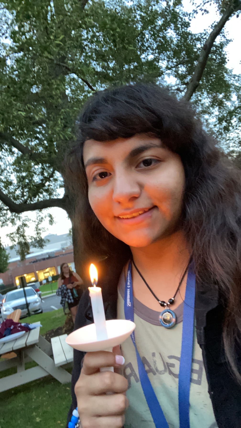 a young woman with dark hair holds a small candle