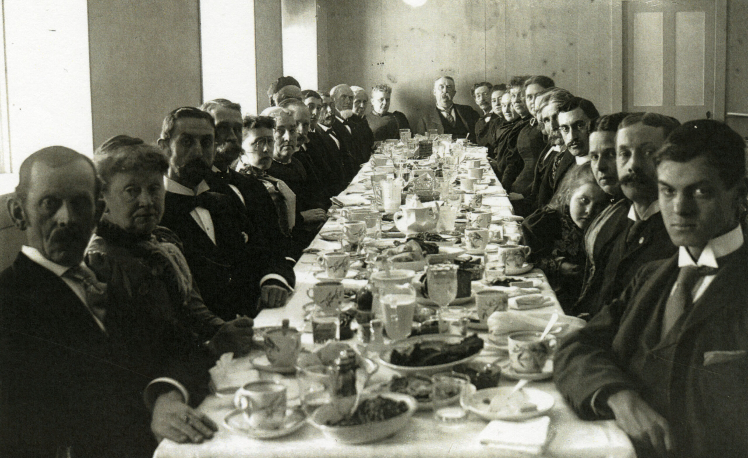 A black and white photo of a large group seated around a table for a birthday party