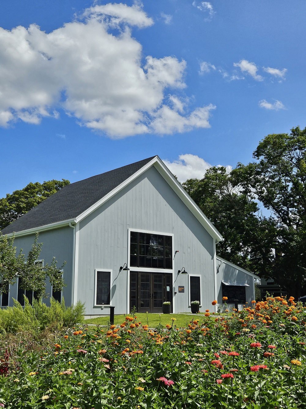 a white barn set against a blue sky with wildflowers in the foreground