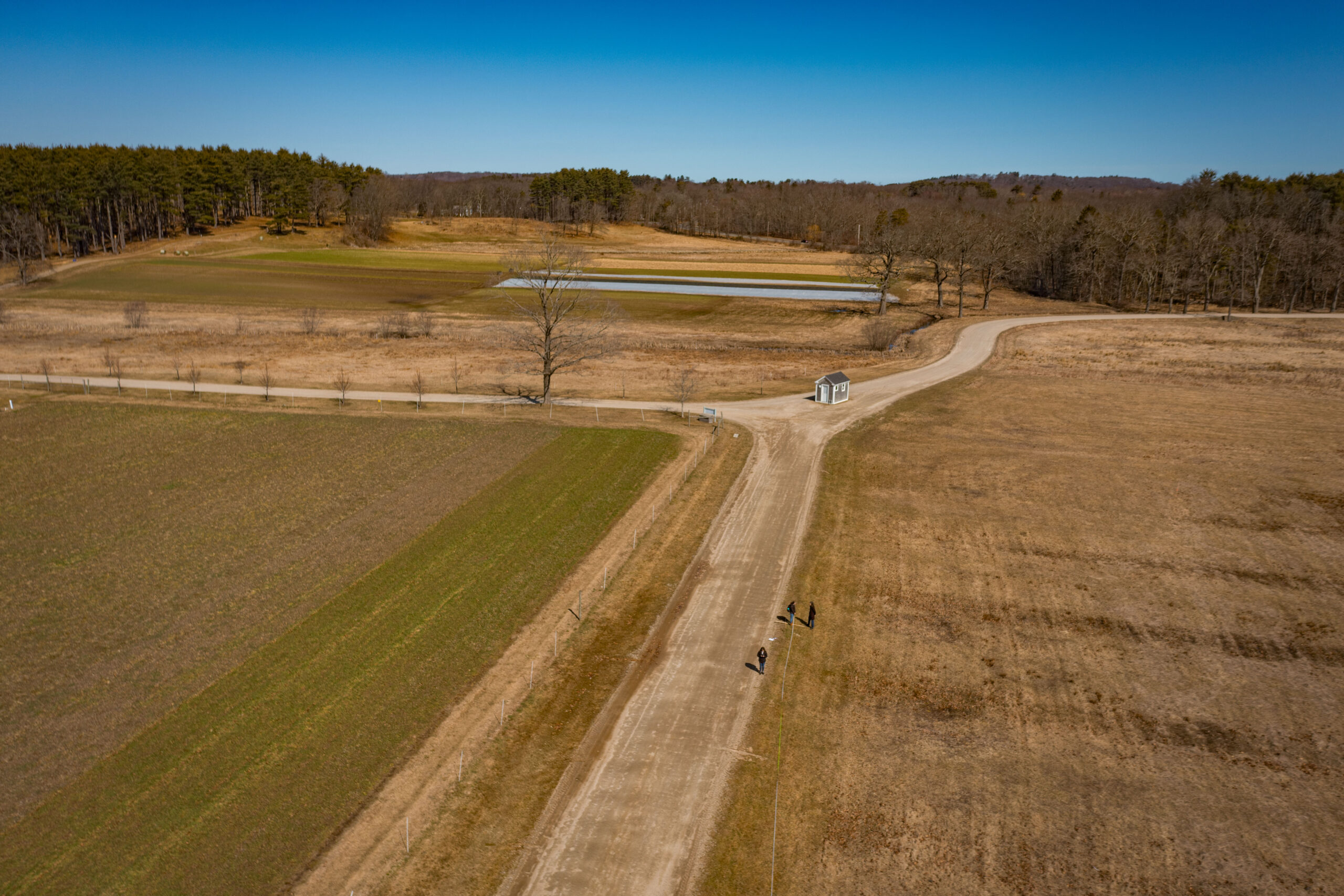 Aerial View of Appleton Farms in March - a road dissects two greenish brown fields.