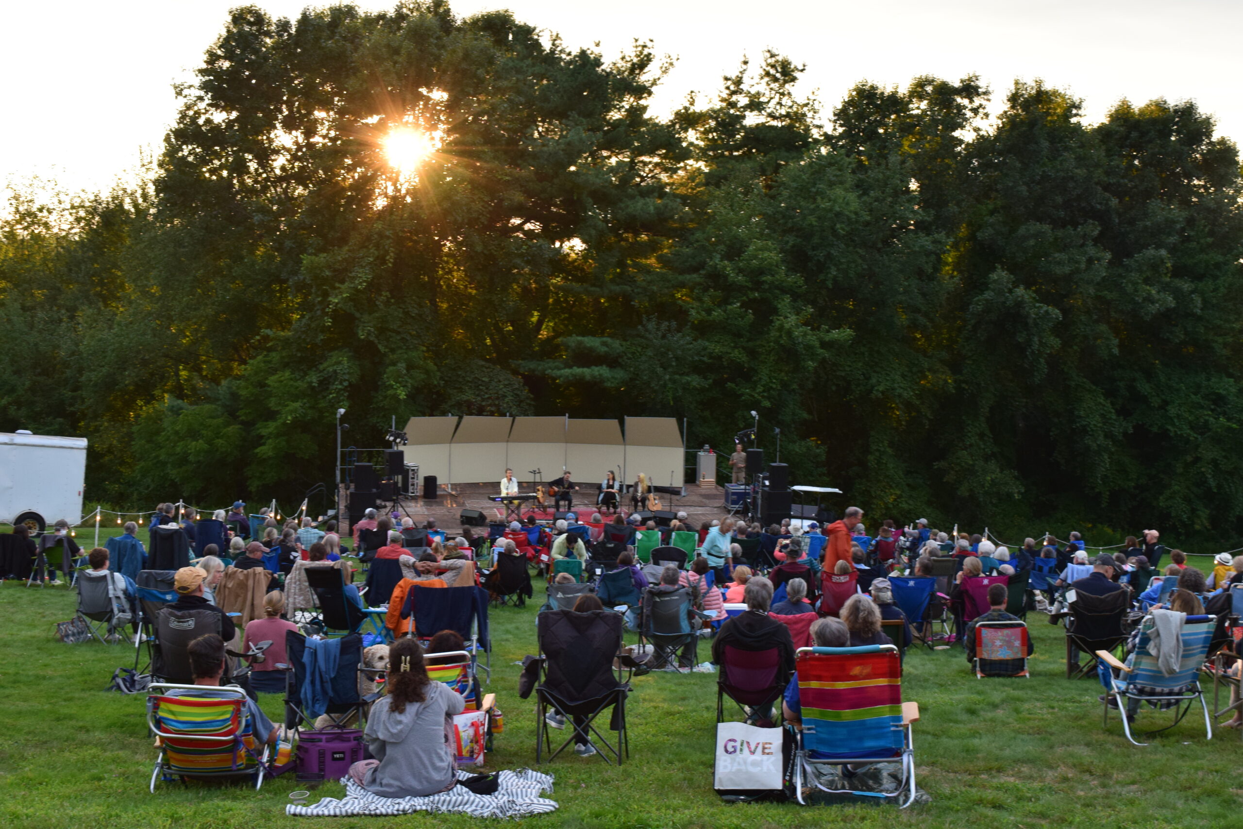 A crowd watches a concert at sunset