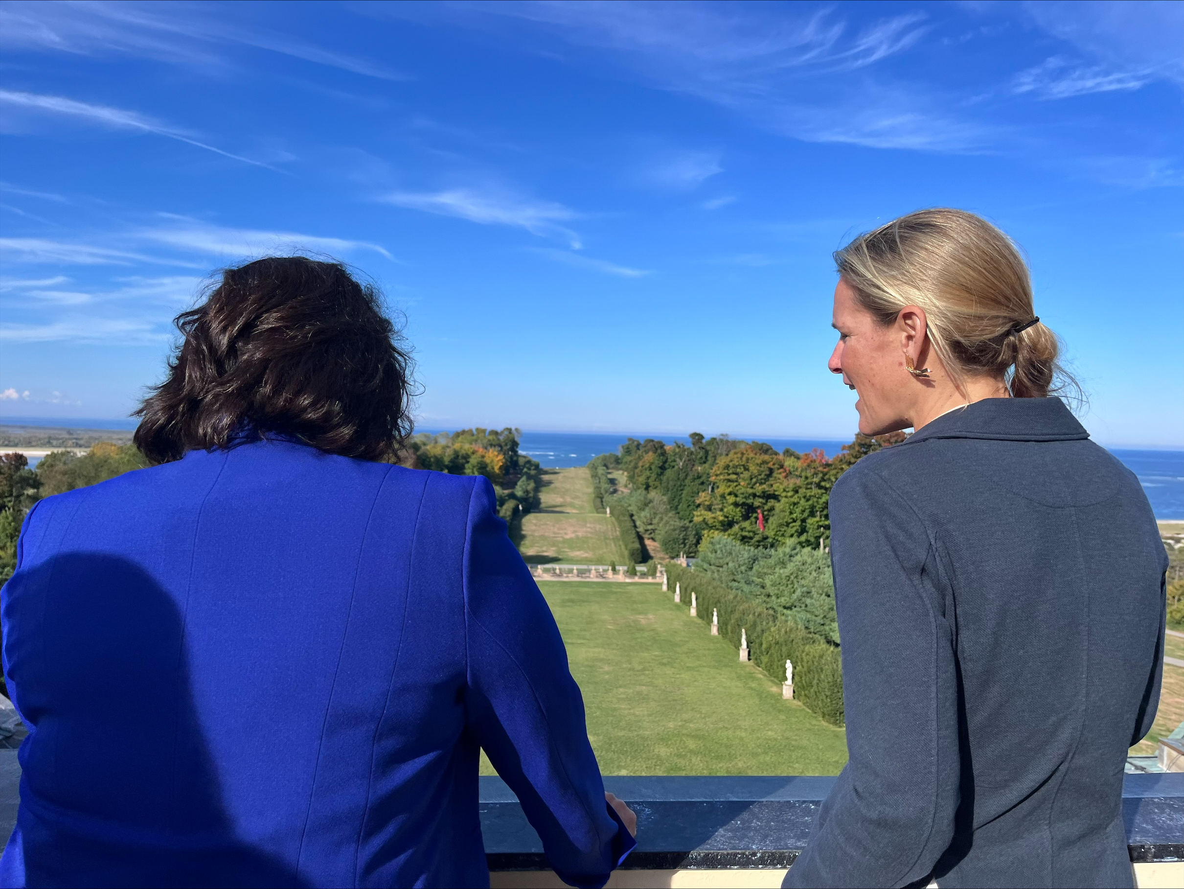 Two women with their backs turned to the camera overlook the Grand Allee at the Crane Estate