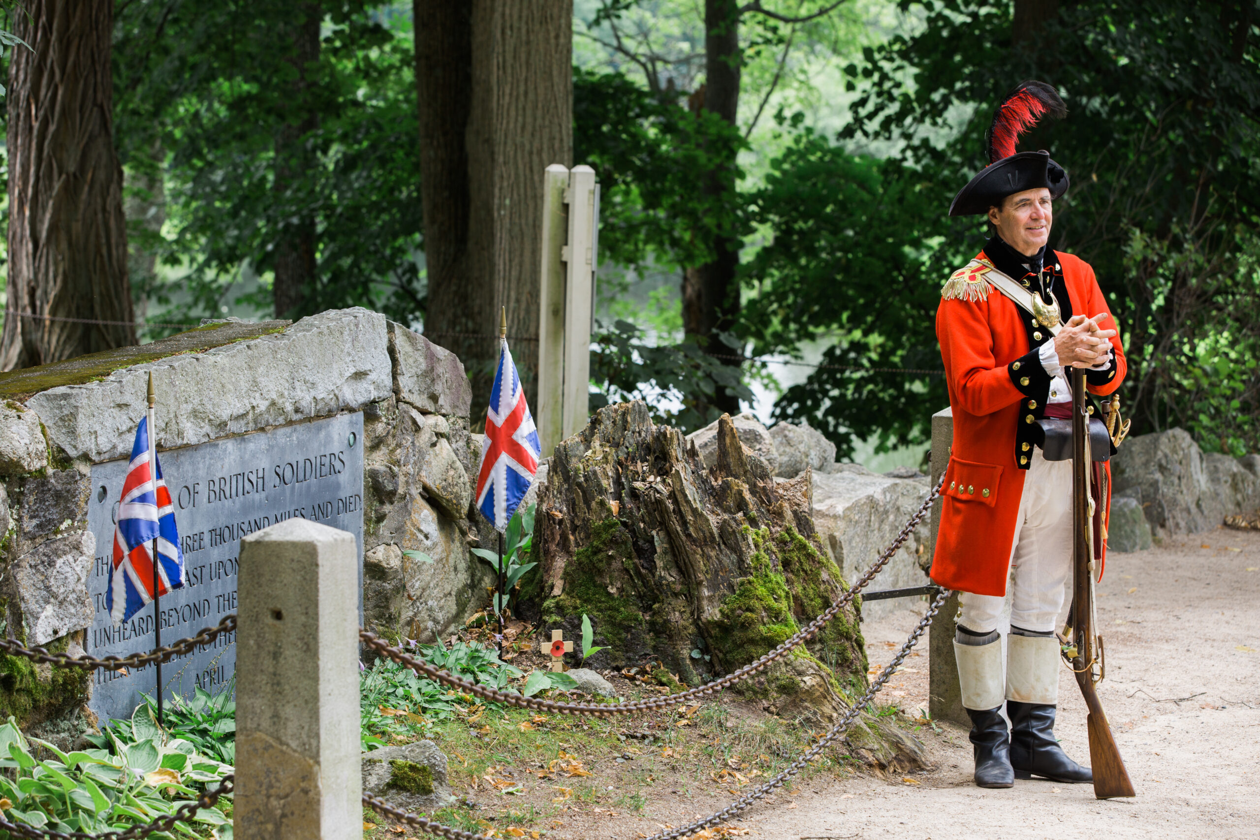 A British Soldier reenactor stands in front of a plaque commemorating the British Soldiers during the battle of Concord.