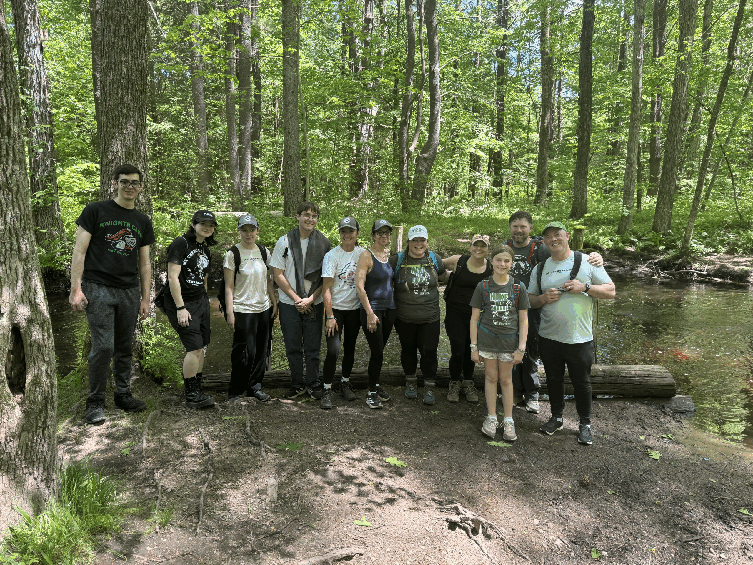 Several people smile at the camera on a trail in a green forest
