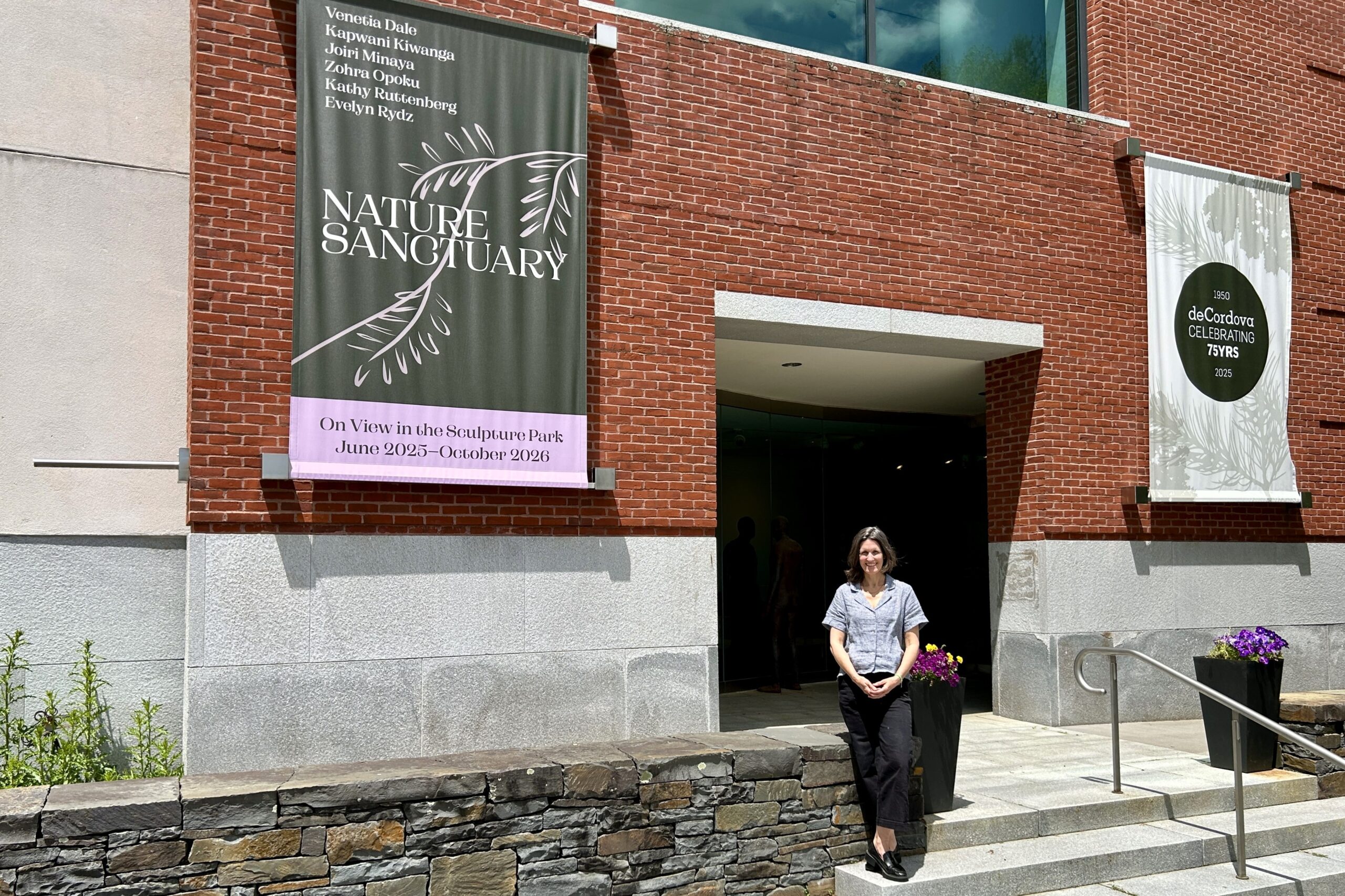 Sarah Montross, Museum Director and Chief Curator of deCordova, stands in front of a sign for