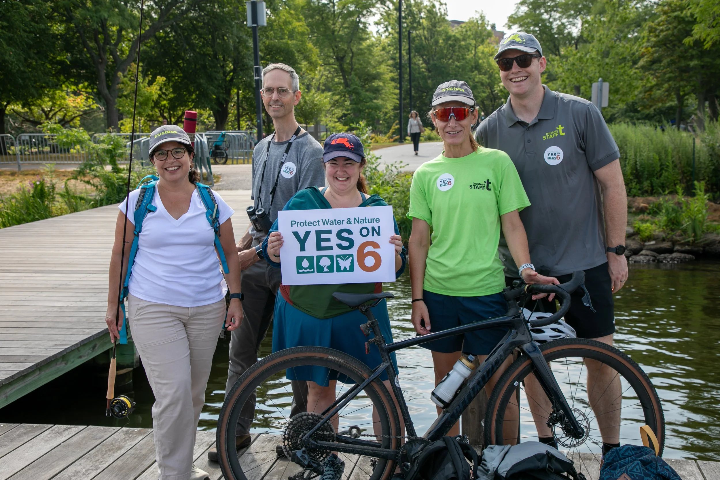 Katie Theoharides, President & CEO of The Trustees, stands next to a mountain bike and four Trustees staff members at the Vote Yes on 6 Launch.