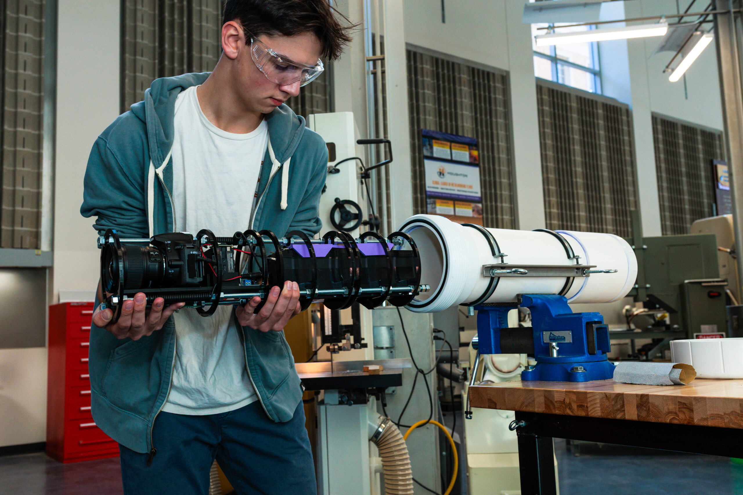 A student in protective eye goggles assembles an unxderwater camera trap.