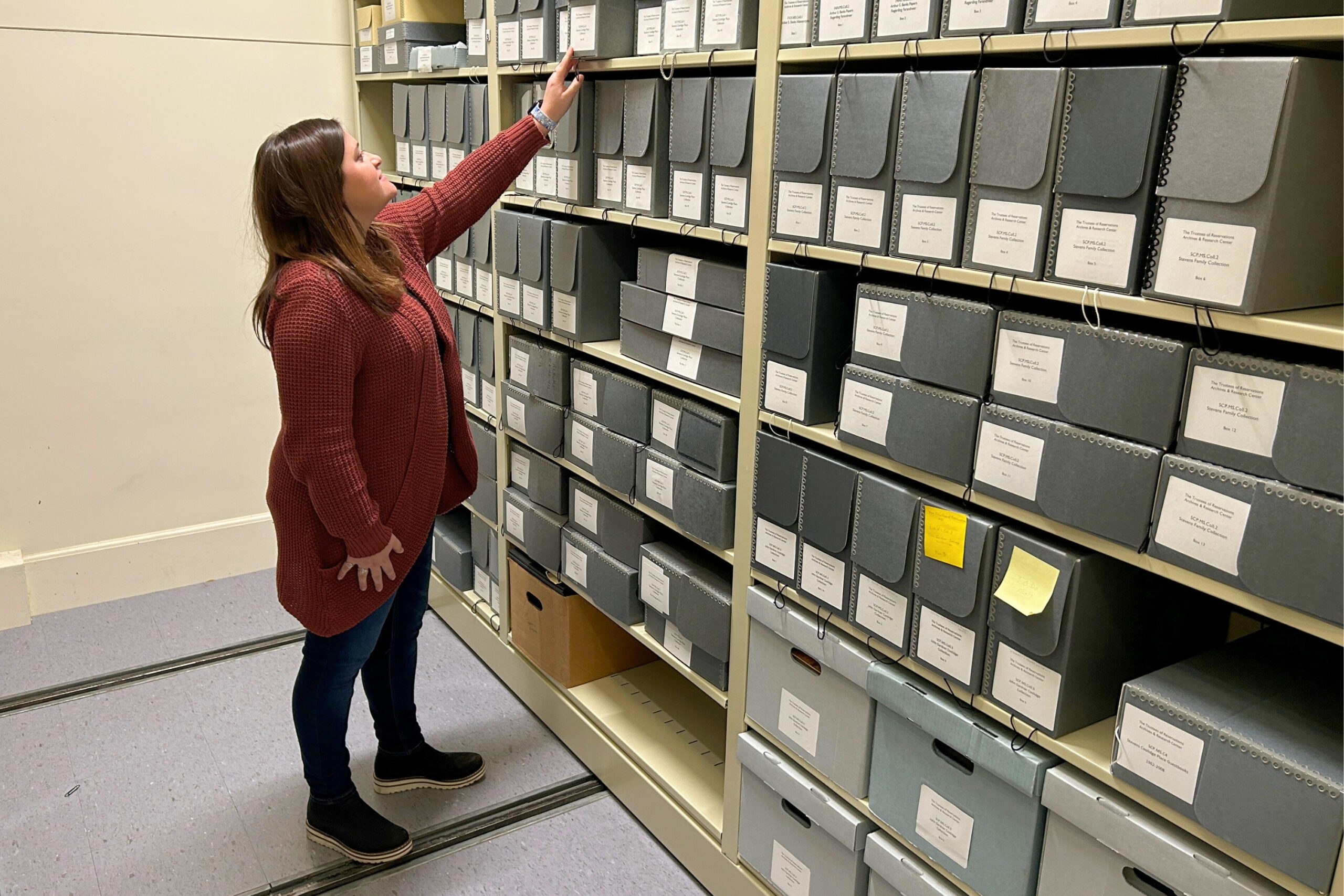 Trustees Archivist Madison Mark pulls a box of archival materials off one of the Archives & Research Center’s stacks.