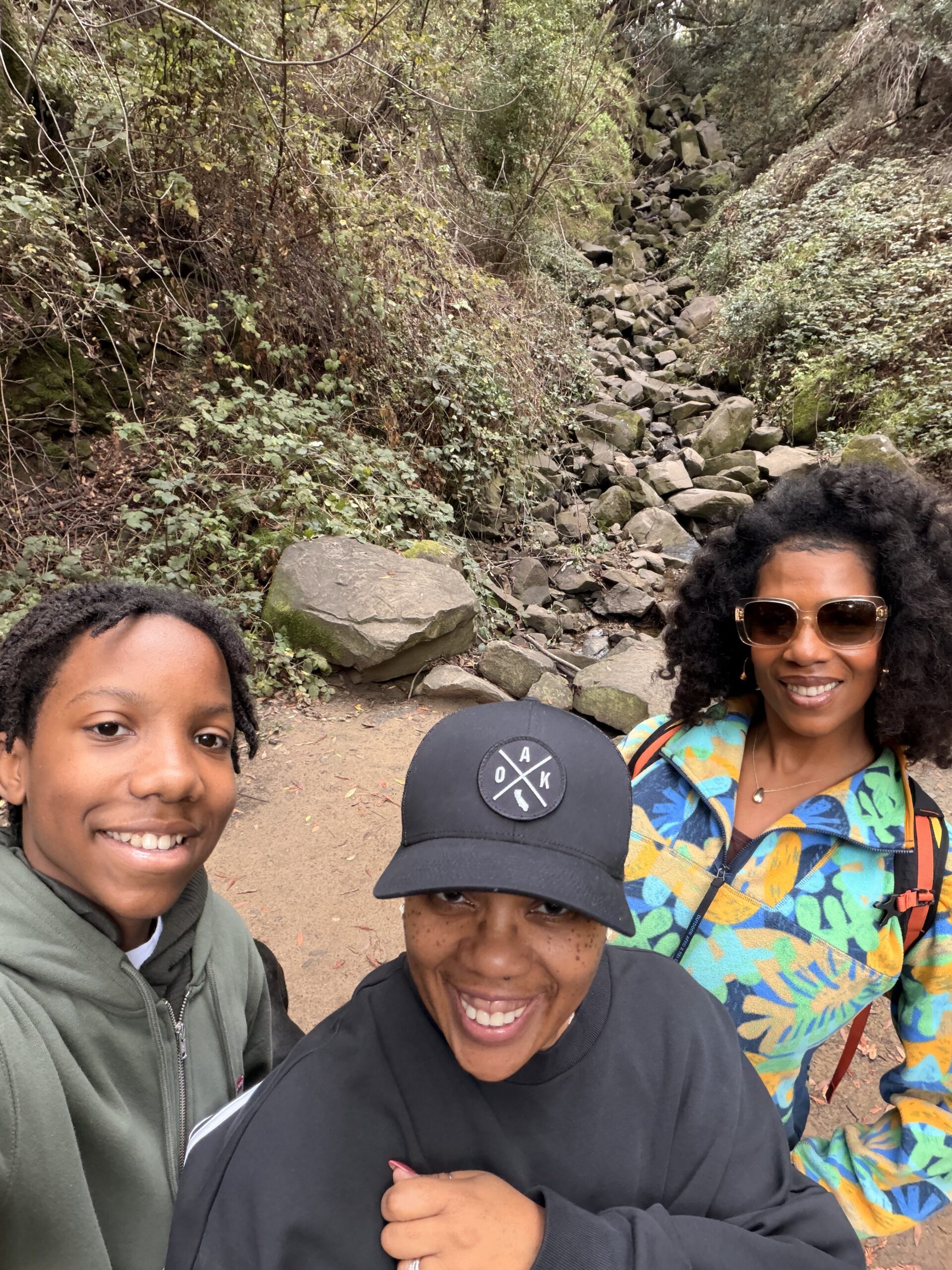 Three people smile up at the camera for a selfie.