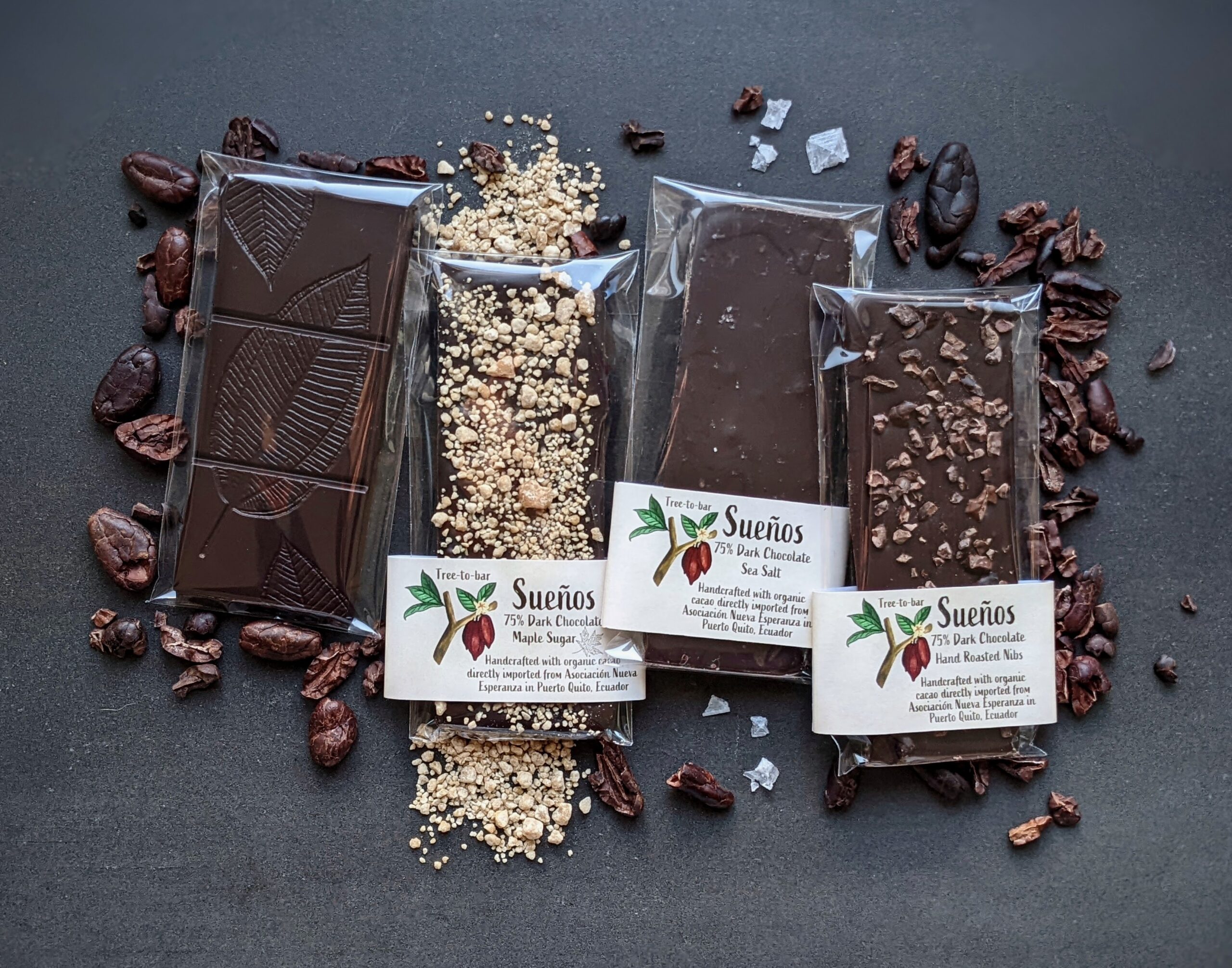 A collection of chocolate bars with business cards for Sueños Chocolates.