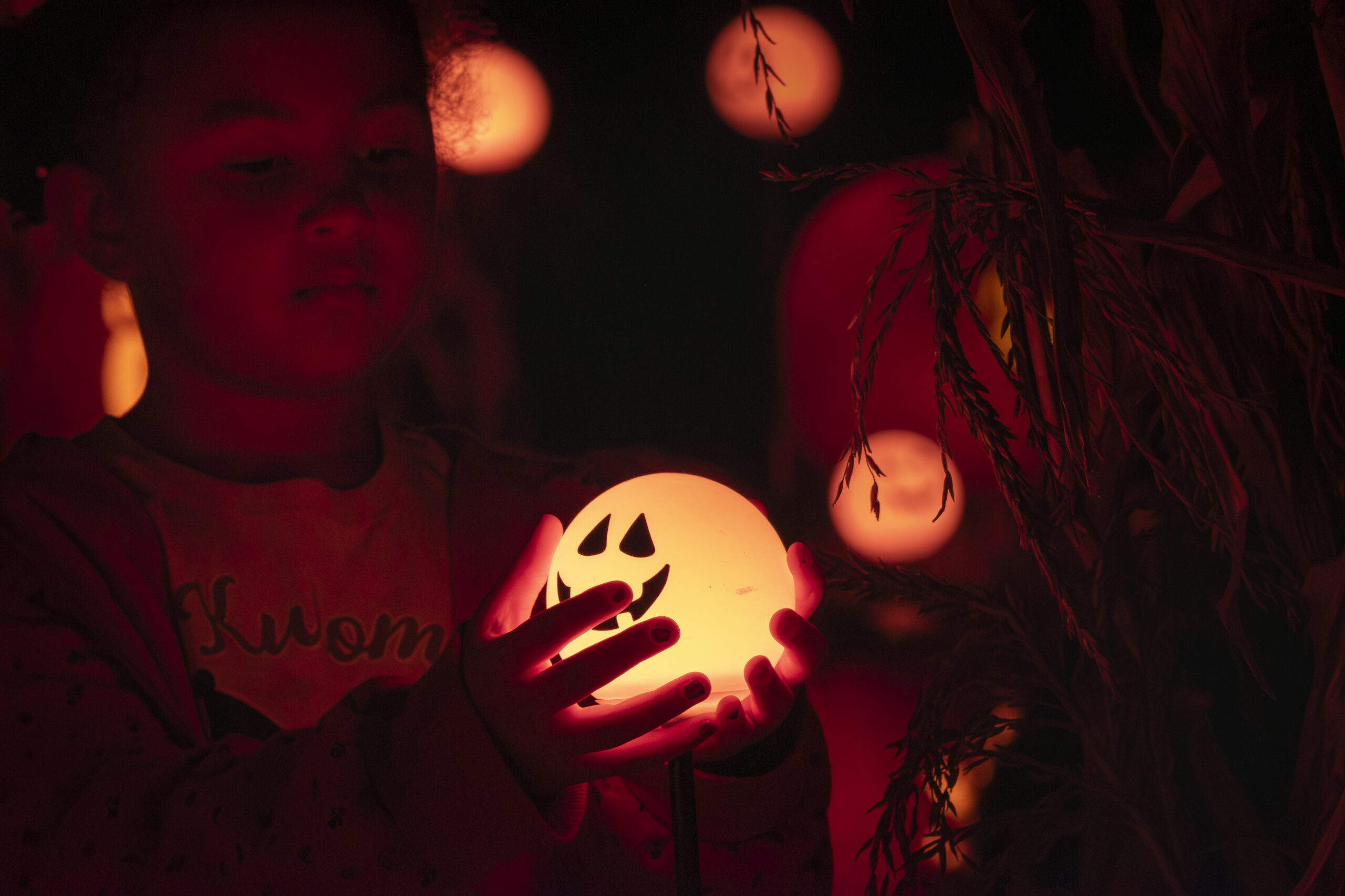 A young student holds a glowing orange pumpkin light at The Incredible Naumkeag Pumpkin Show